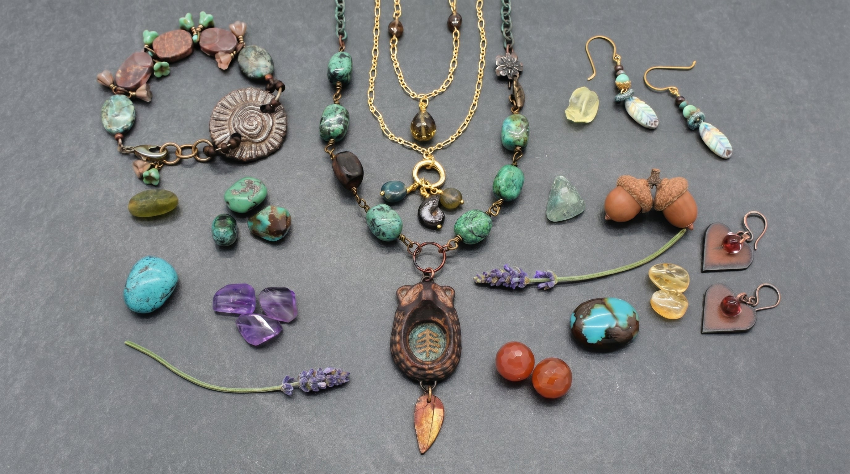 An assortment of handmade one of kind necklaces, bracelets, and earrings, along with sprigs of lavender and colorful beads - Layering Jewelry Blog by Ruby Acorn