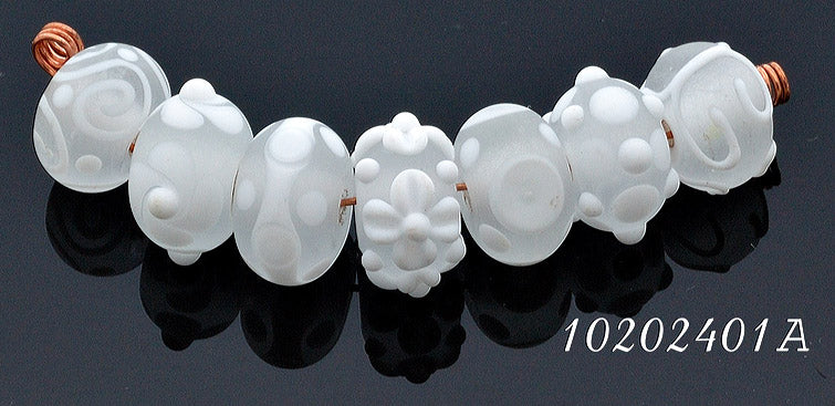 White lampwork glass rondelle beads by Grace Ma with raised floral and dot details and a frosted matte finish.