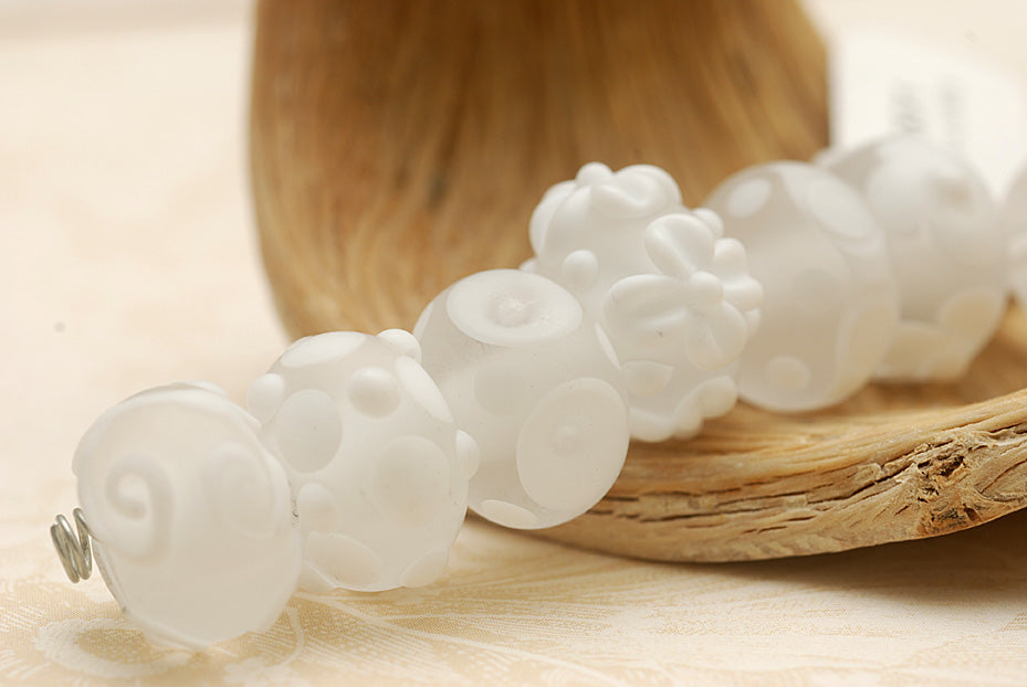 White lampwork beads on a wooden surface