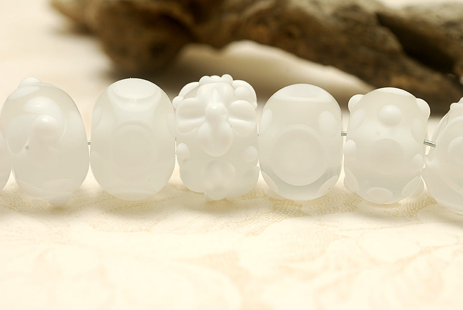 White lampwork glass rondelle beads by Grace Ma with raised floral and dot details and a frosted matte finish.