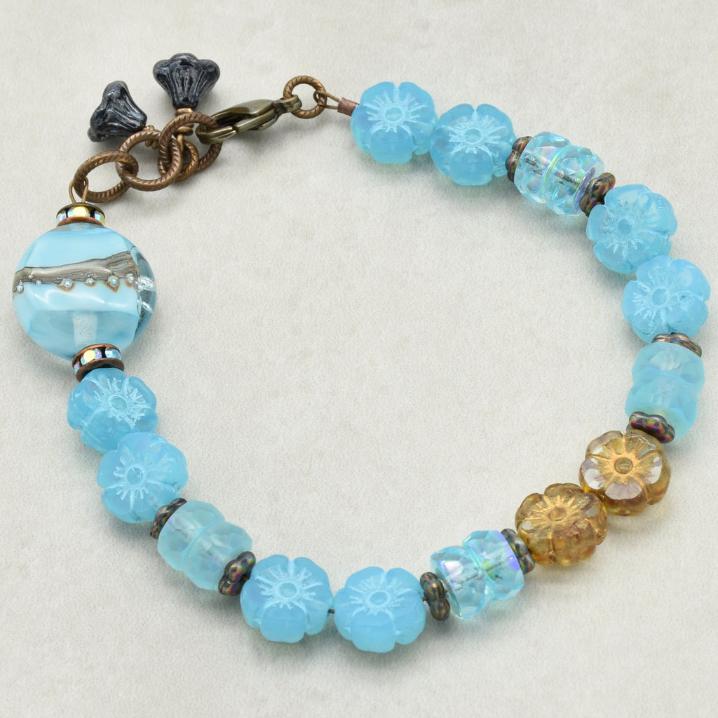 Blue beaded bracelet with floral patterns on a white background