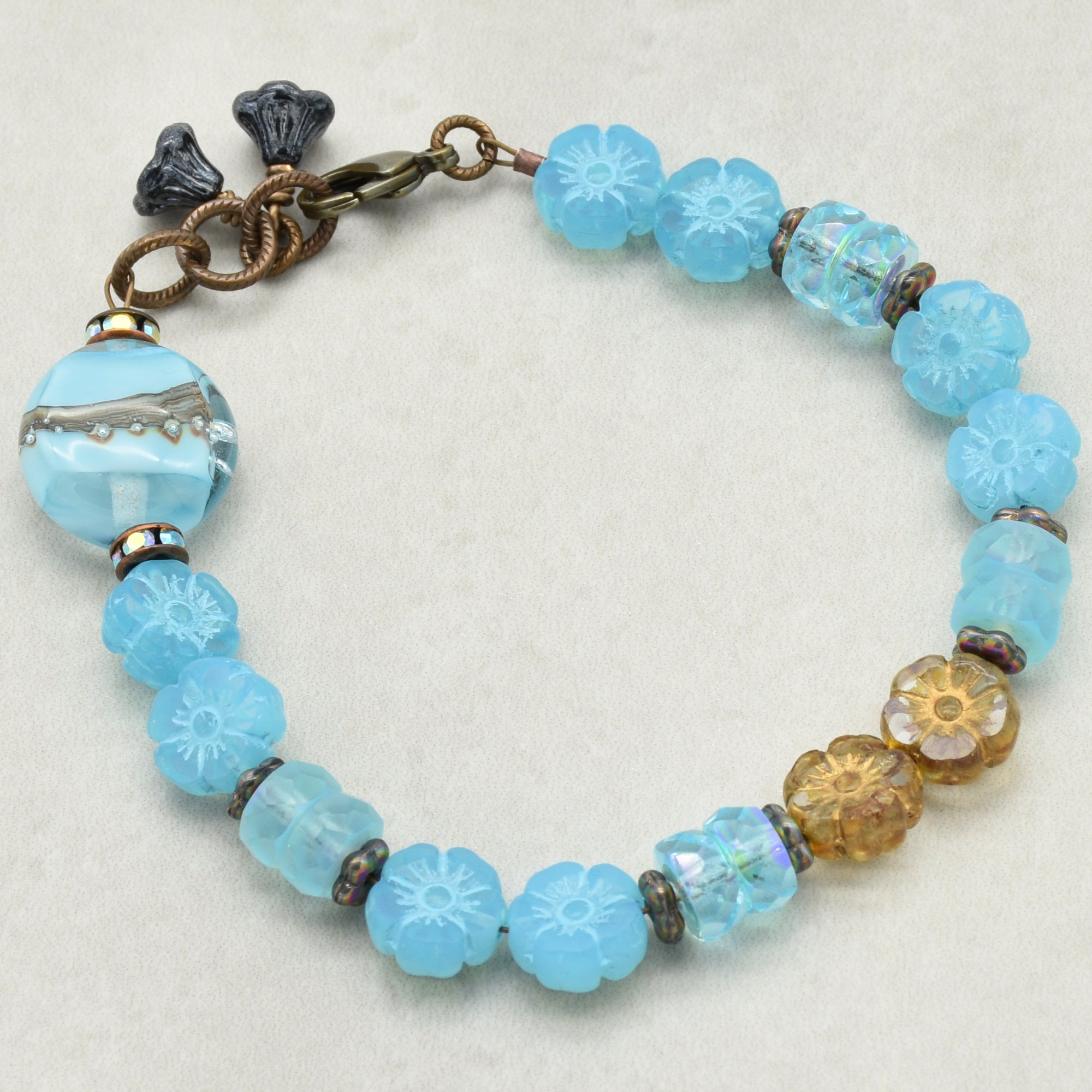 Blue beaded bracelet with floral patterns on a white background