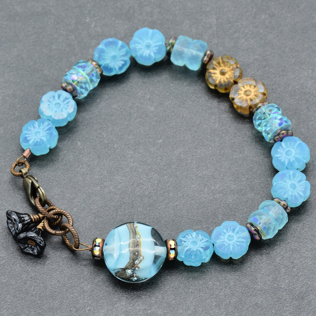 Beaded bracelet with blue and gold beads on a gray background