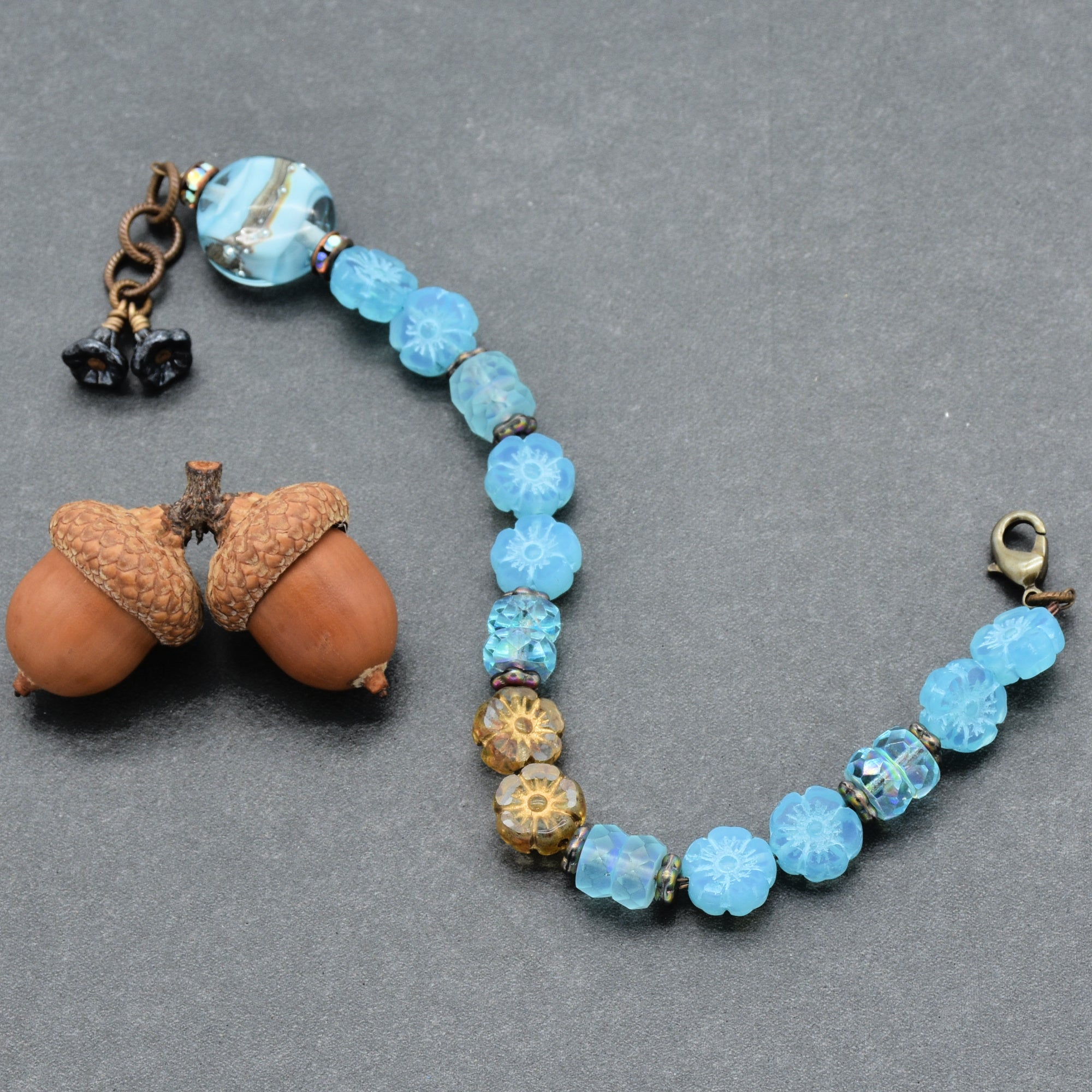 Beaded bracelet with blue beads and a lobster clasp on a gray background