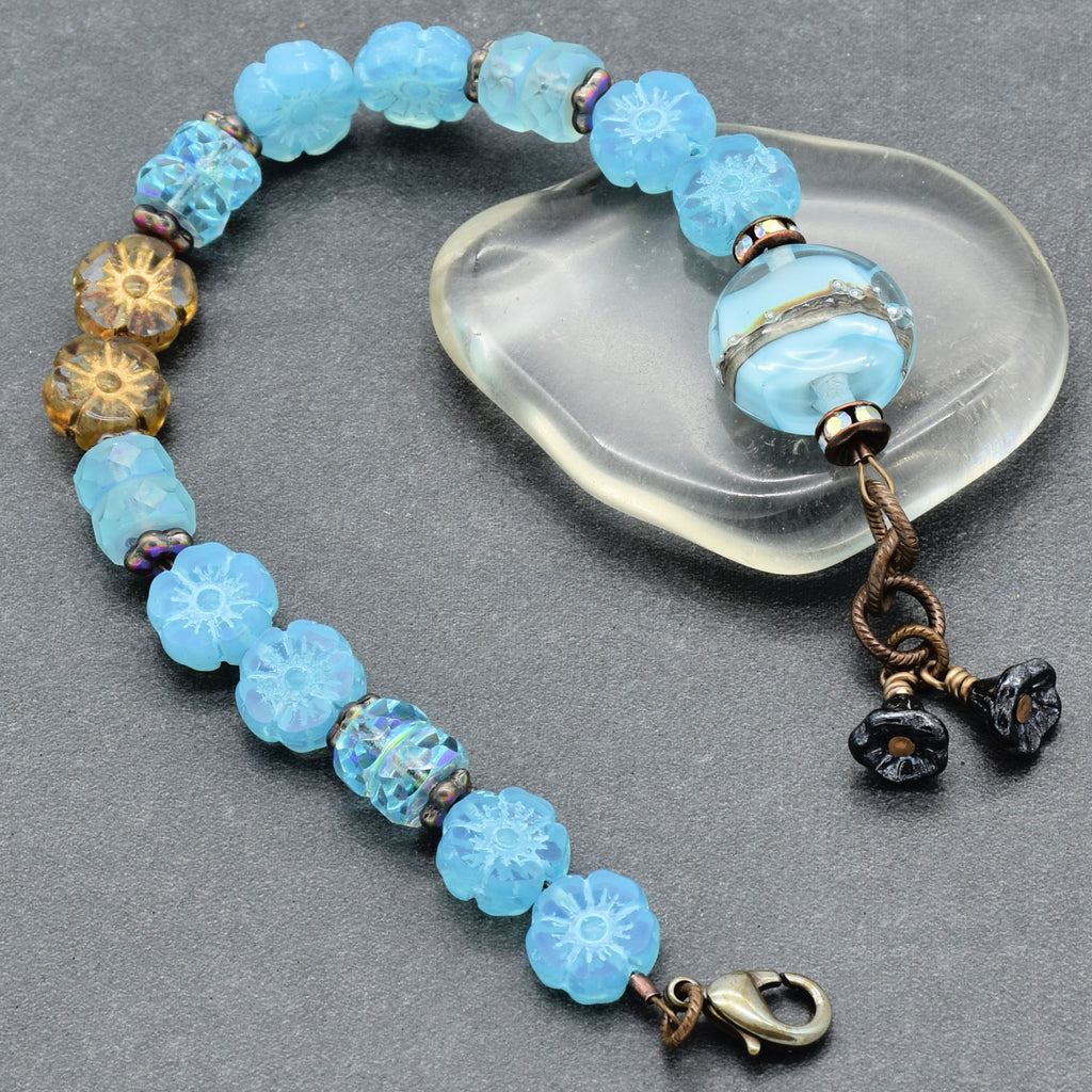 Blue beaded bracelet with floral designs on a gray surface