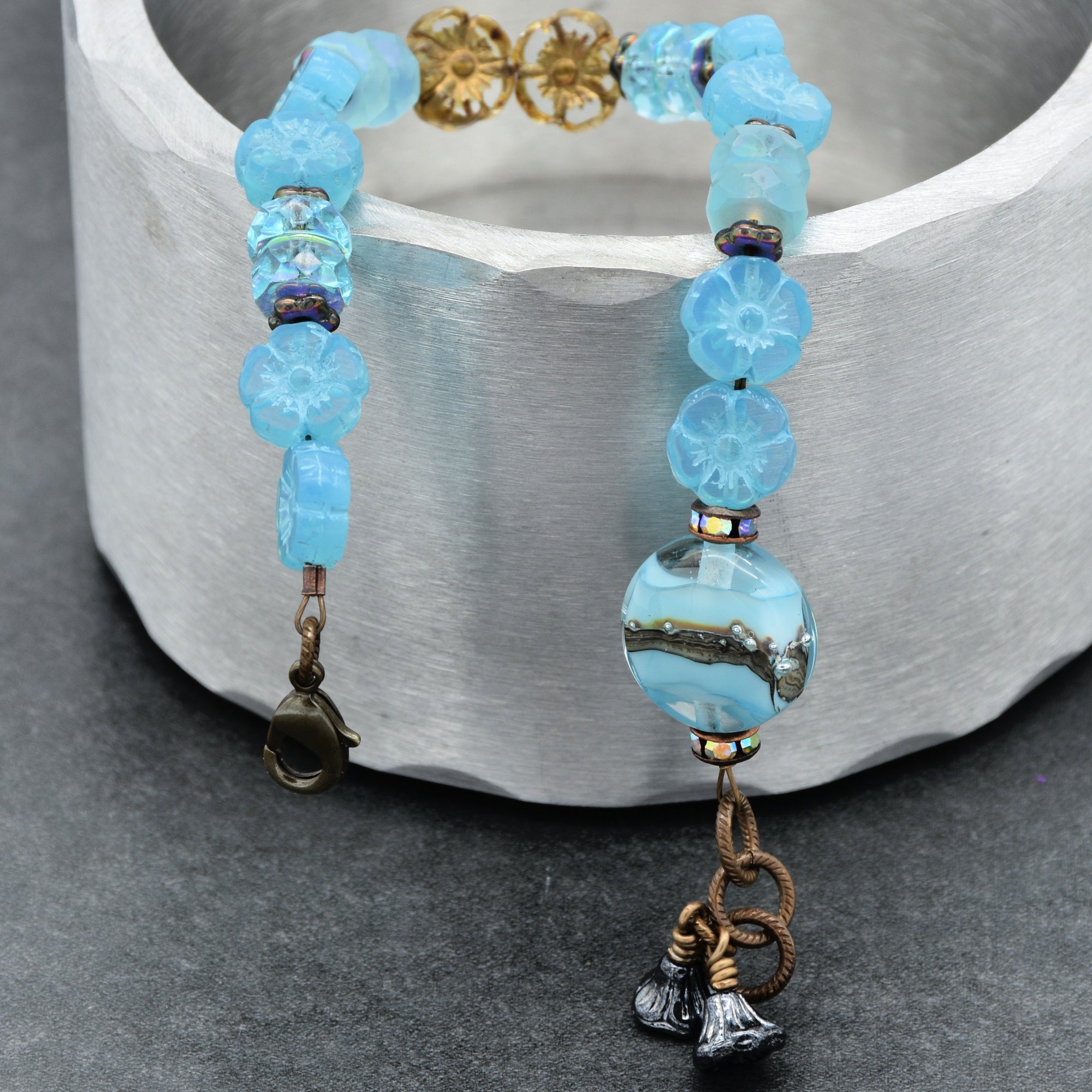 Beaded bracelet with blue beads and decorative elements on a gray surface