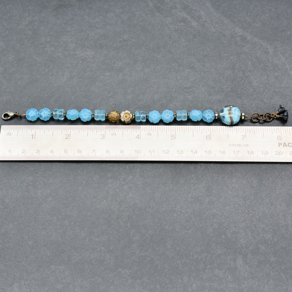Beaded bracelet with blue and gold beads on a gray surface with a ruler for scale.
