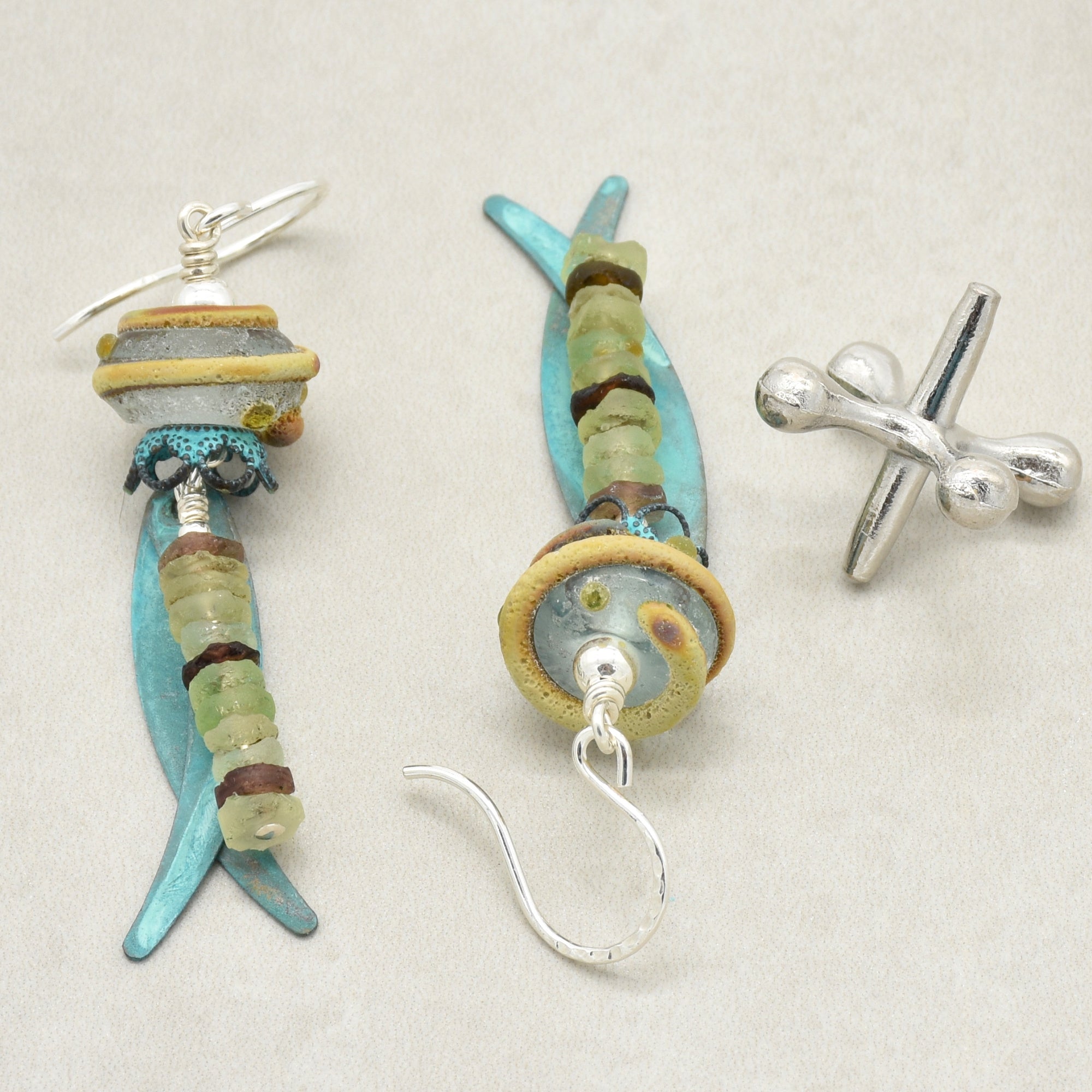 Handmade ancient Roman glass earrings  with artisan lampwork glass, verdigris daggers, and silver ear wires on a neutral beige background - made with love in Colorado by Ruby Acorn.
