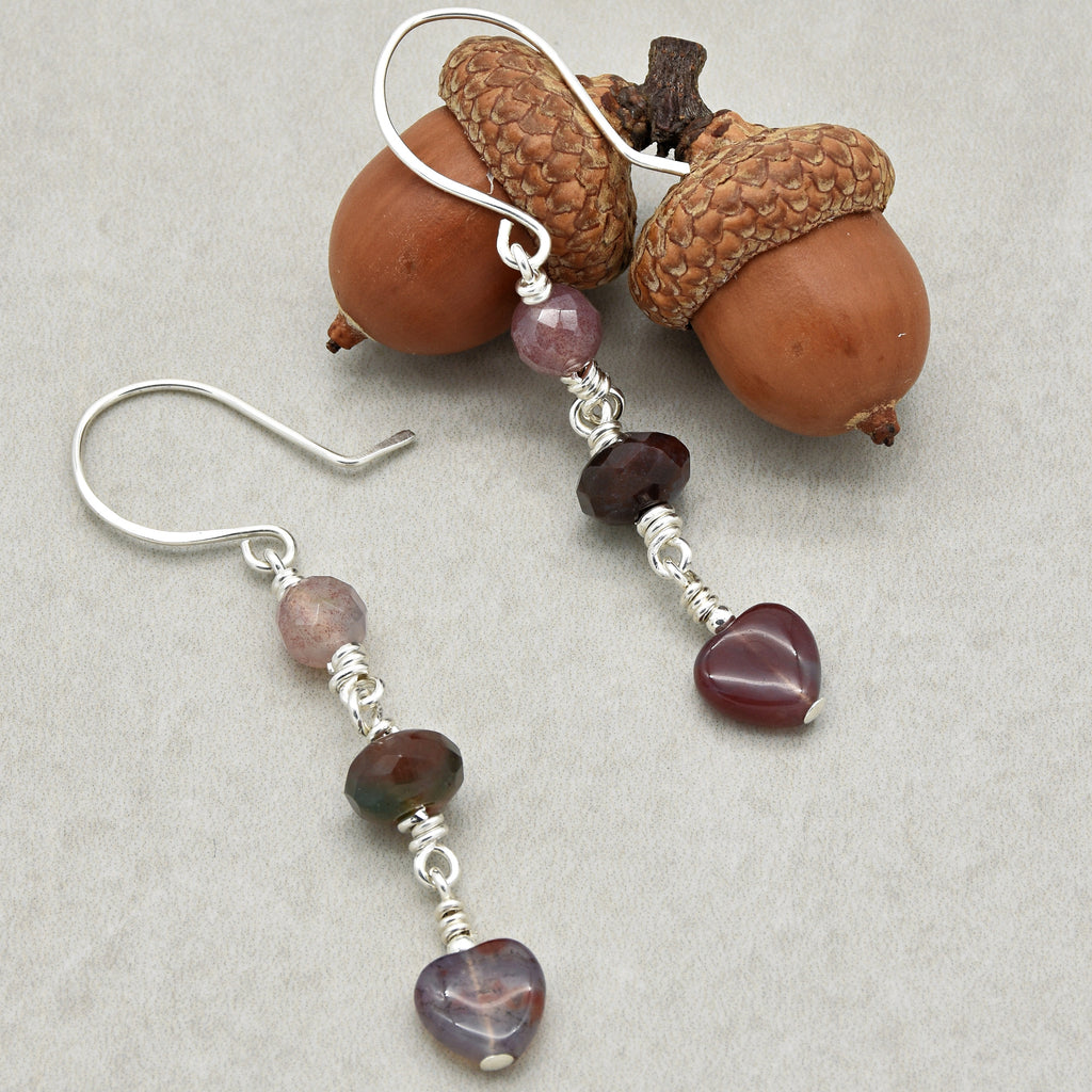 This image shows a pair of earrings. They have hooks for wearing on pierced ears and are decorated with beads and heart-shaped charms.