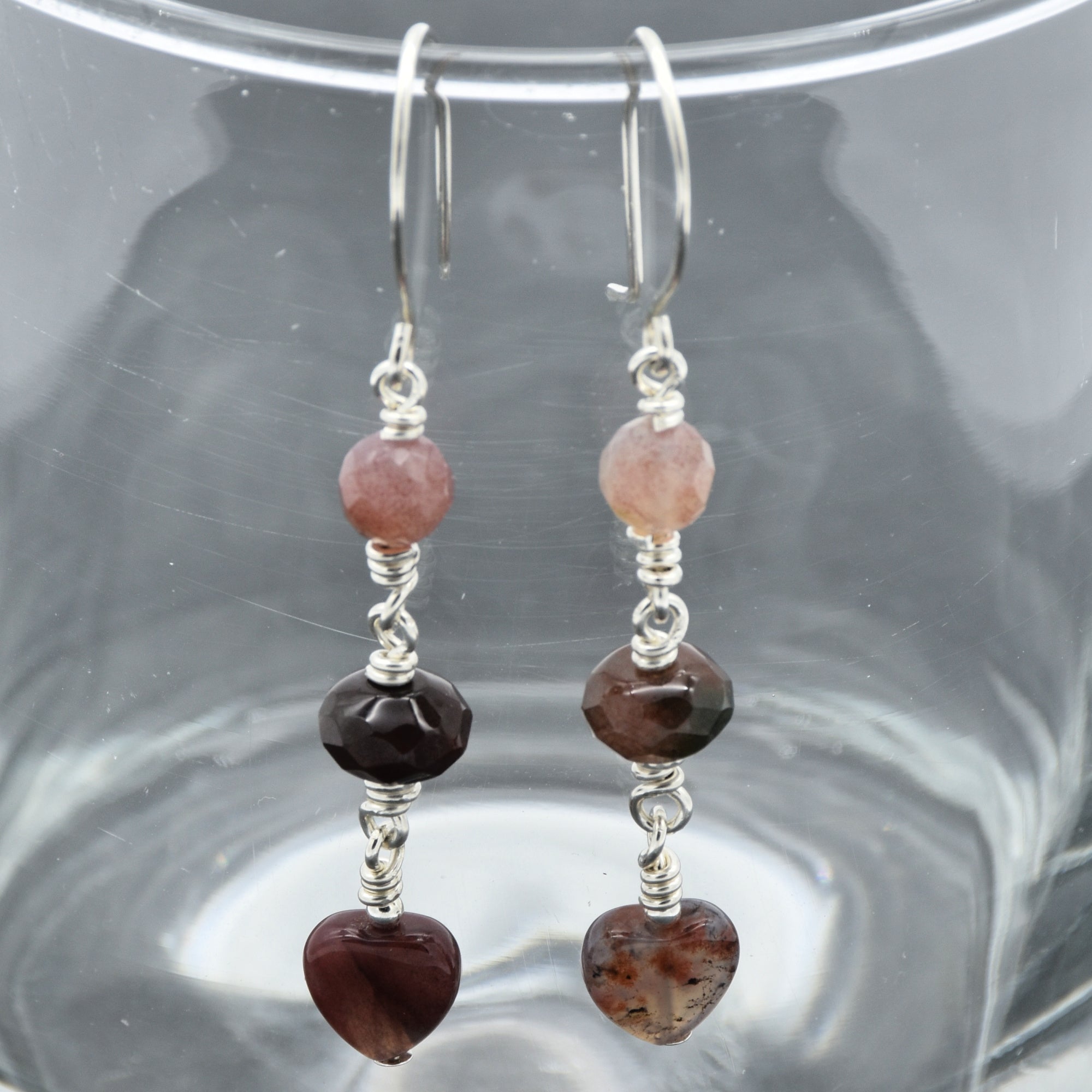 The image shows a pair of earrings. They are dangly earrings with multiple beads, including heart-shaped beads at the bottom, and they are attached to hooks for wearing in pierced ears.