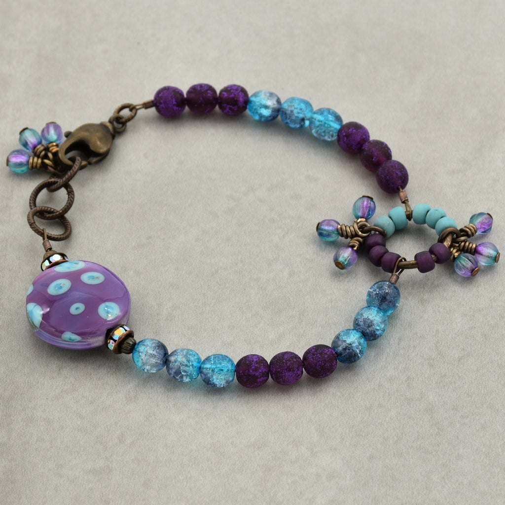Beaded bracelet with purple and blue beads on a beige background