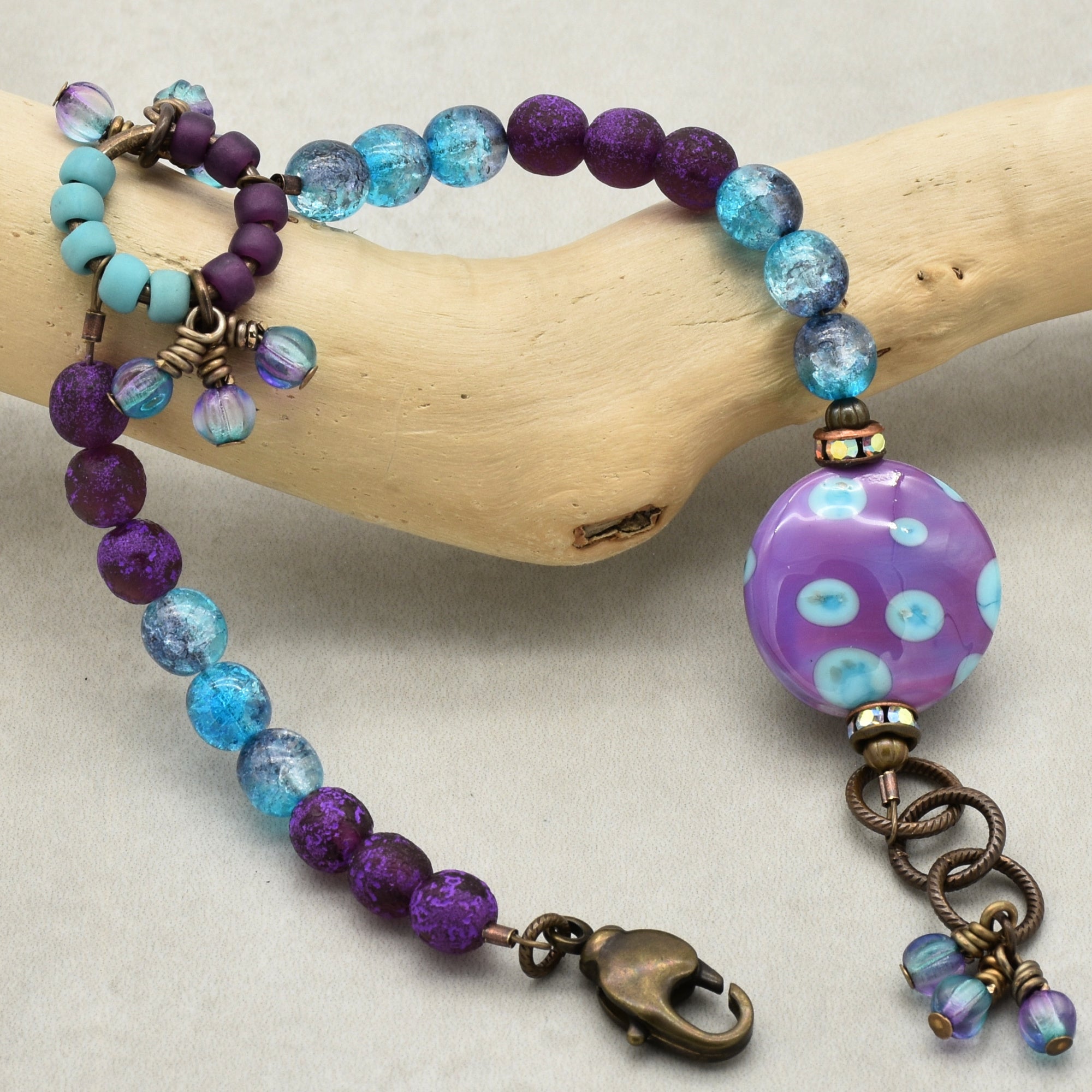 Beaded bracelet with purple and blue beads on a wooden branch