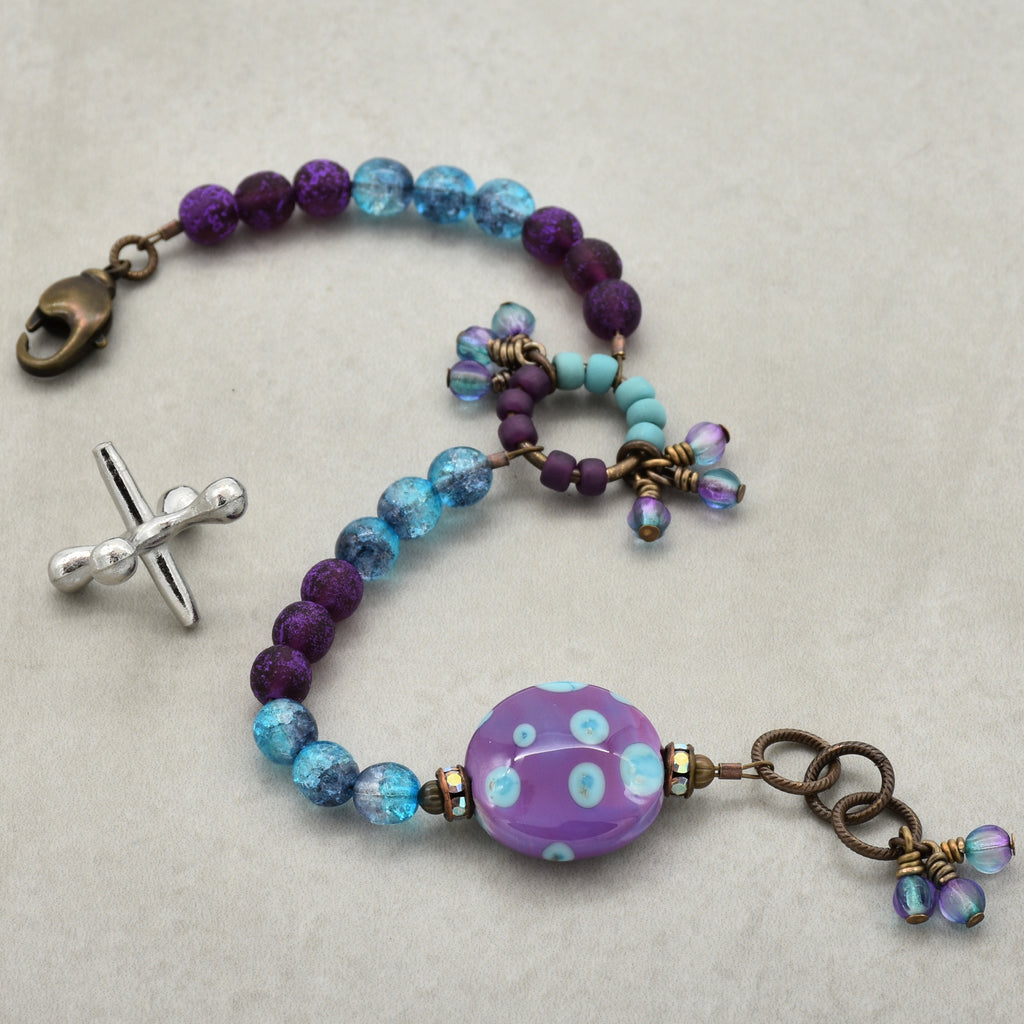 Beaded bracelet with purple and blue beads on a light gray background