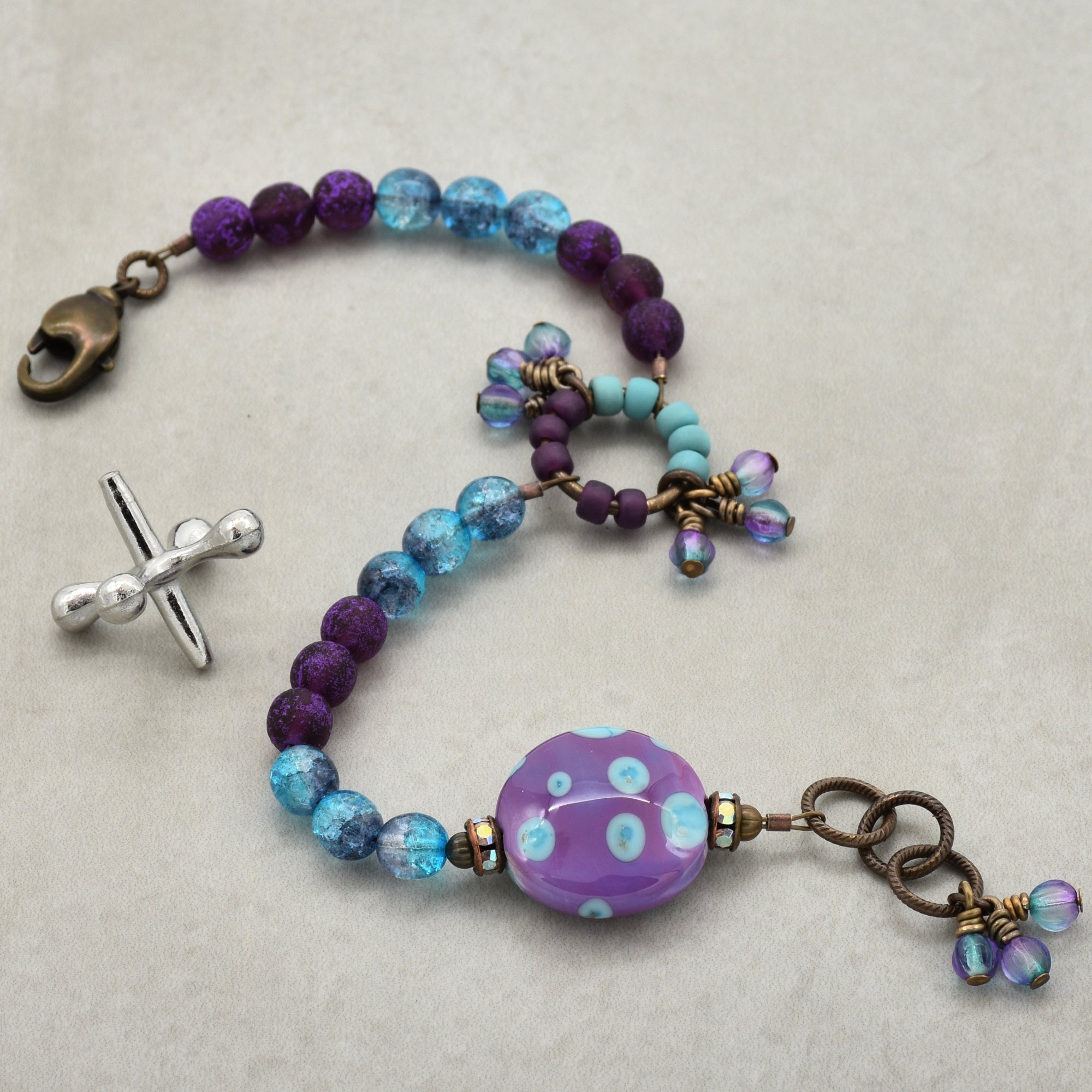 Beaded bracelet with purple and blue beads on a light gray background