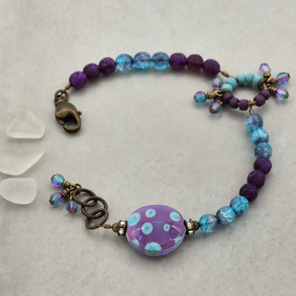 Beaded bracelet with purple and blue beads on a textured surface