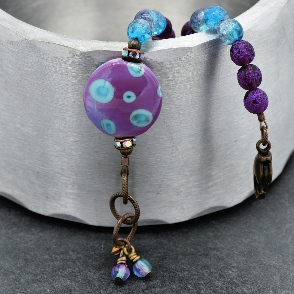 Beaded bracelet with purple and blue beads on a metallic surface