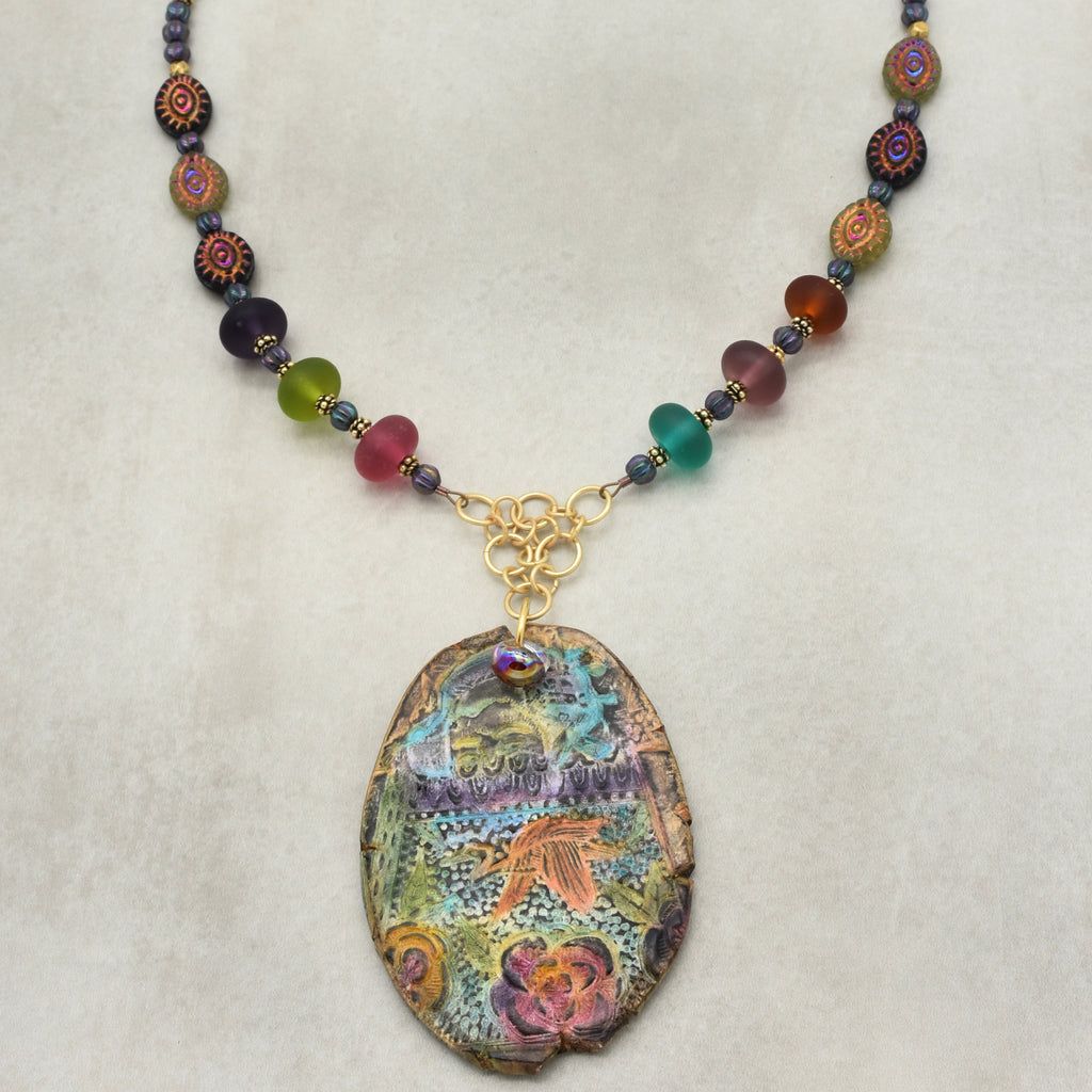 Colorful beaded necklace with a decorative pendant on a light gray background