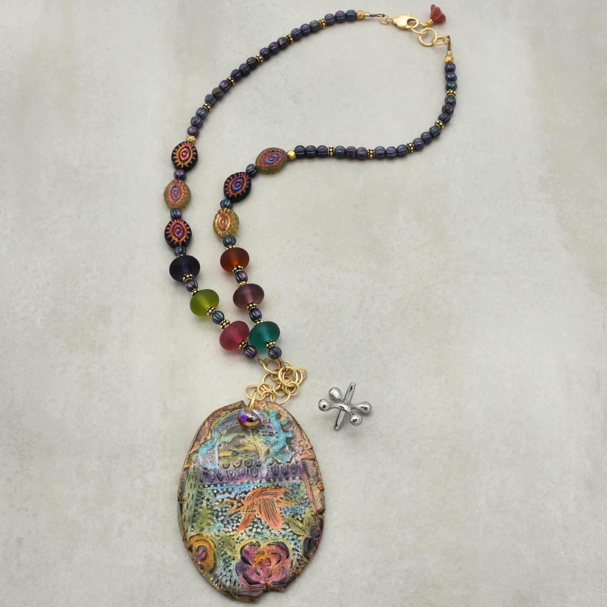 Colorful beaded necklace with a large decorative pendant on a light gray background