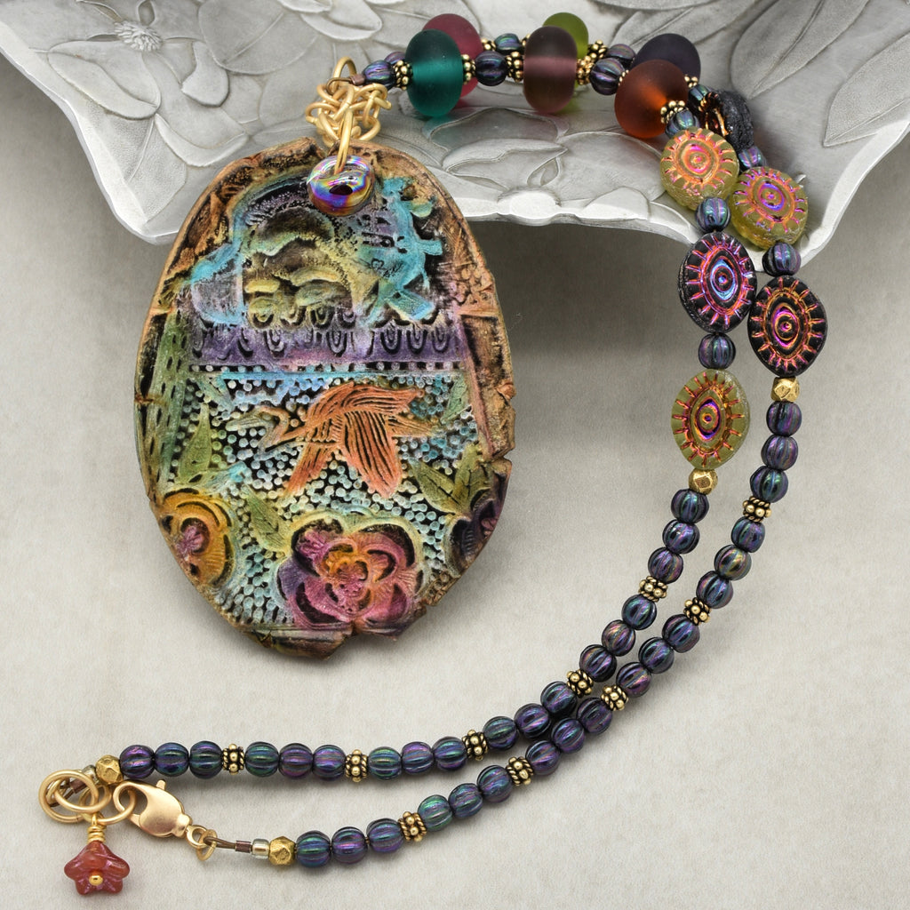 Colorful beaded necklace with an intricately designed pendant on a textured surface