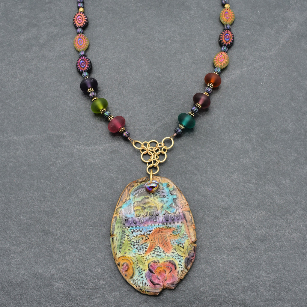 Colorful beaded necklace with a decorative pendant on a gray background
