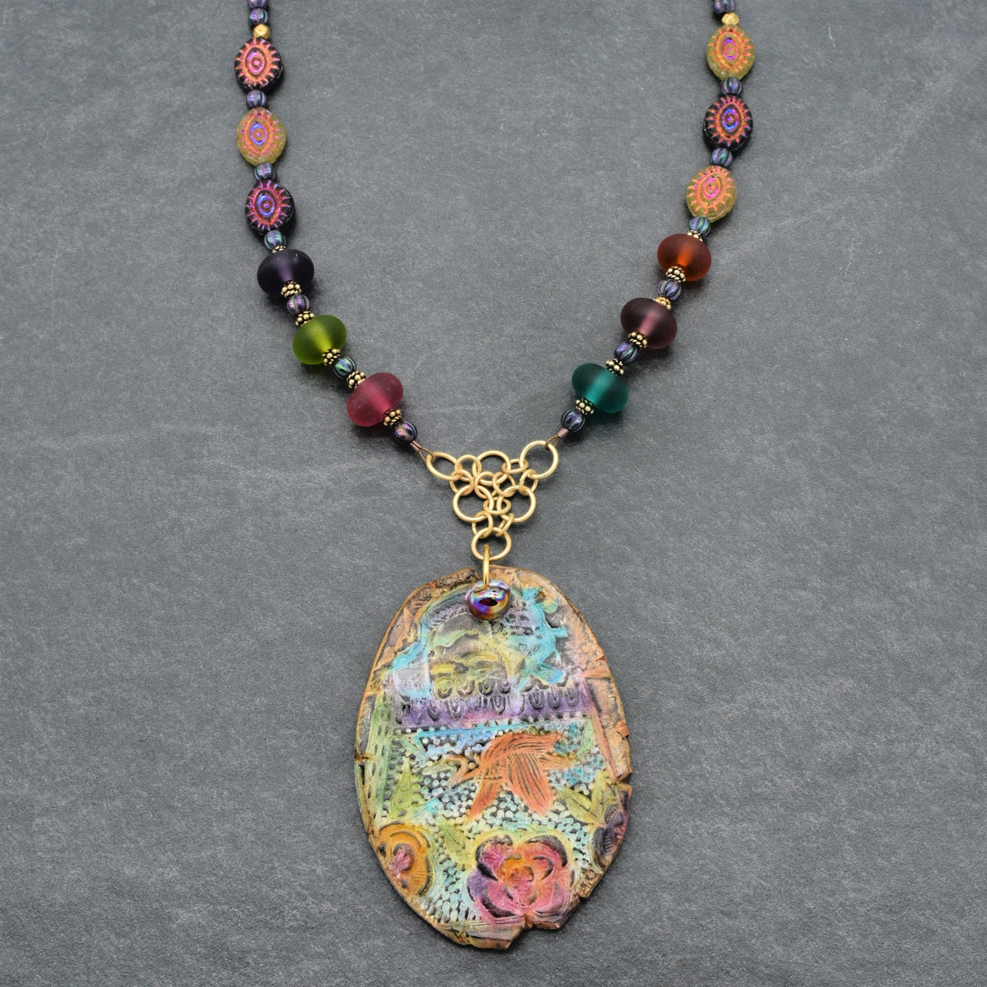 Colorful beaded necklace with a decorative pendant on a gray background