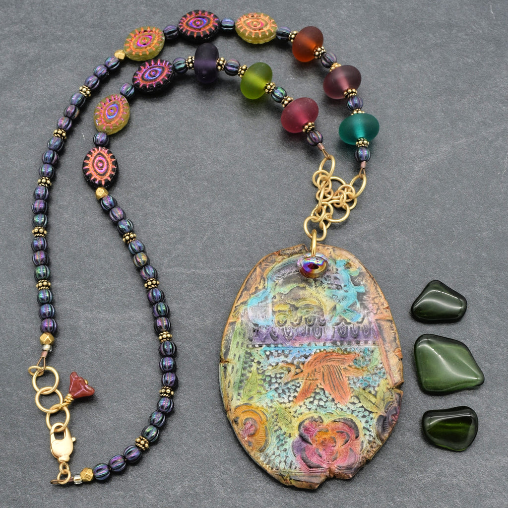Colorful beaded necklace with a large decorative pendant on a gray background