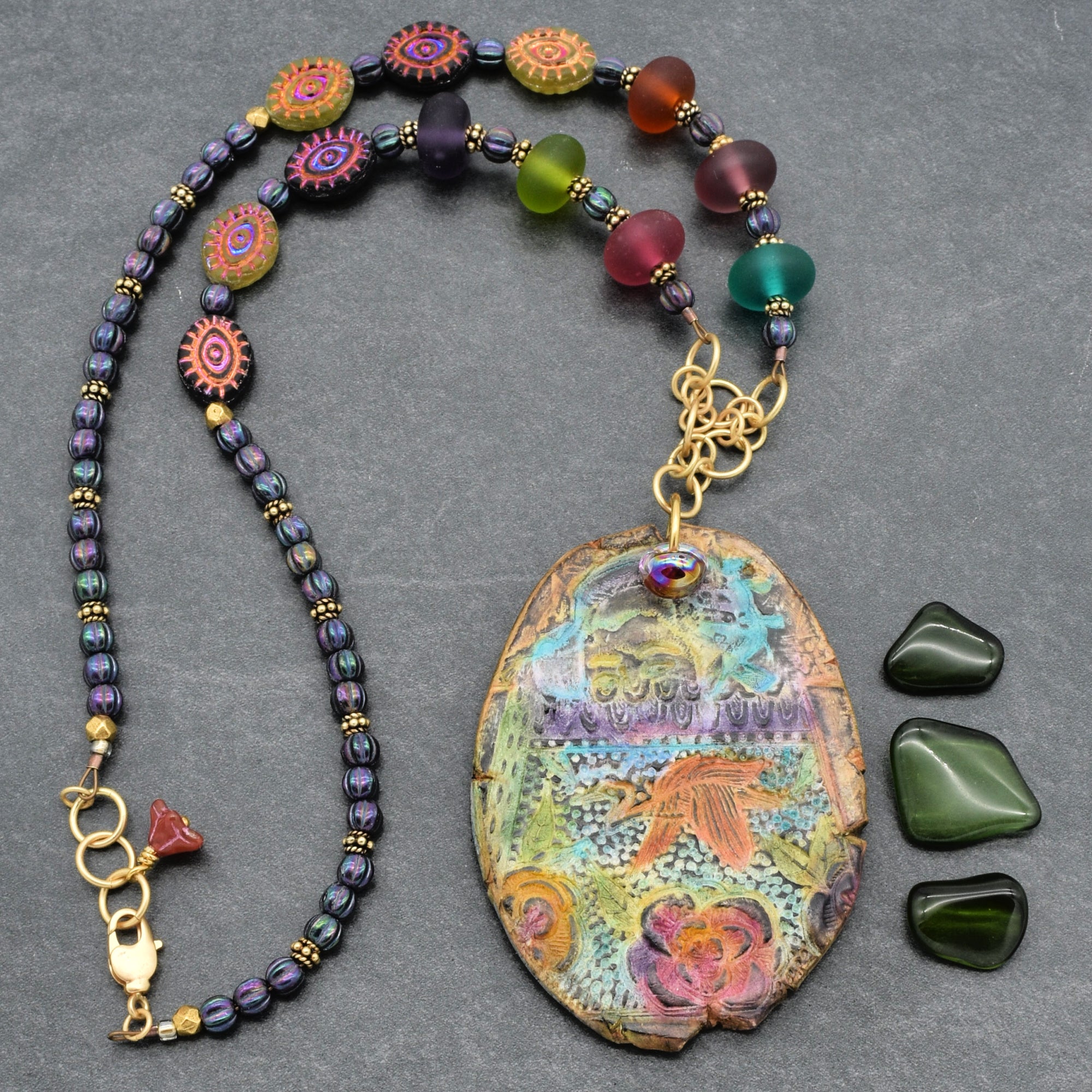 Colorful beaded necklace with a large decorative pendant on a gray background