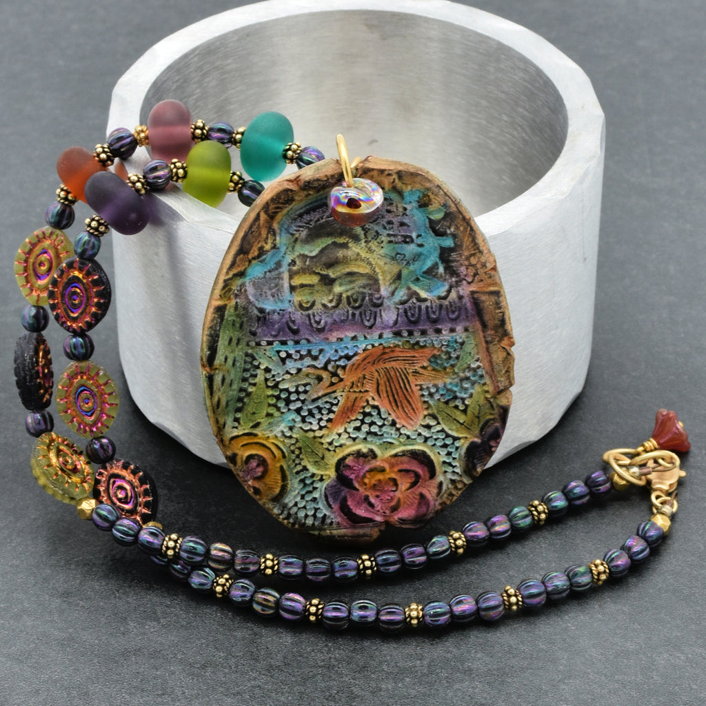 Colorful beaded necklace with a decorative pendant on a gray background