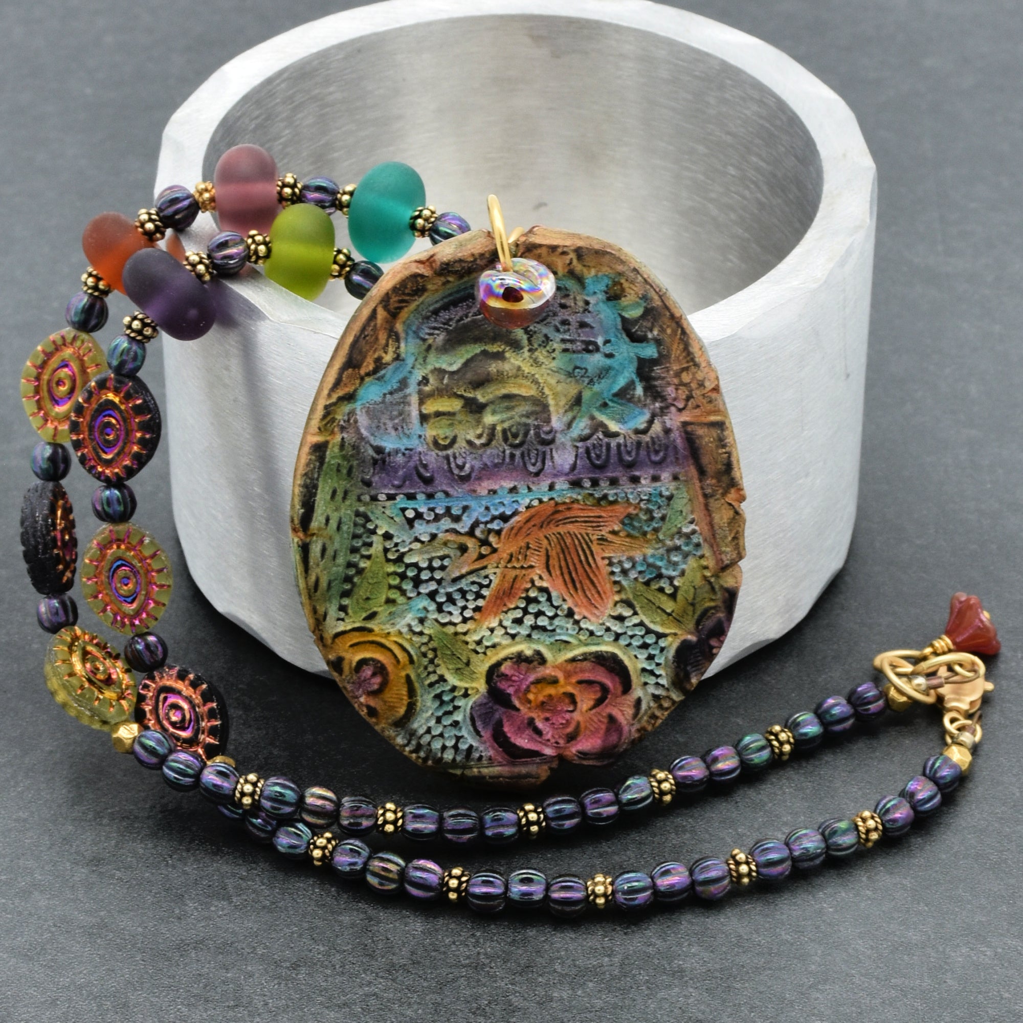 Colorful beaded necklace with a decorative pendant on a gray background