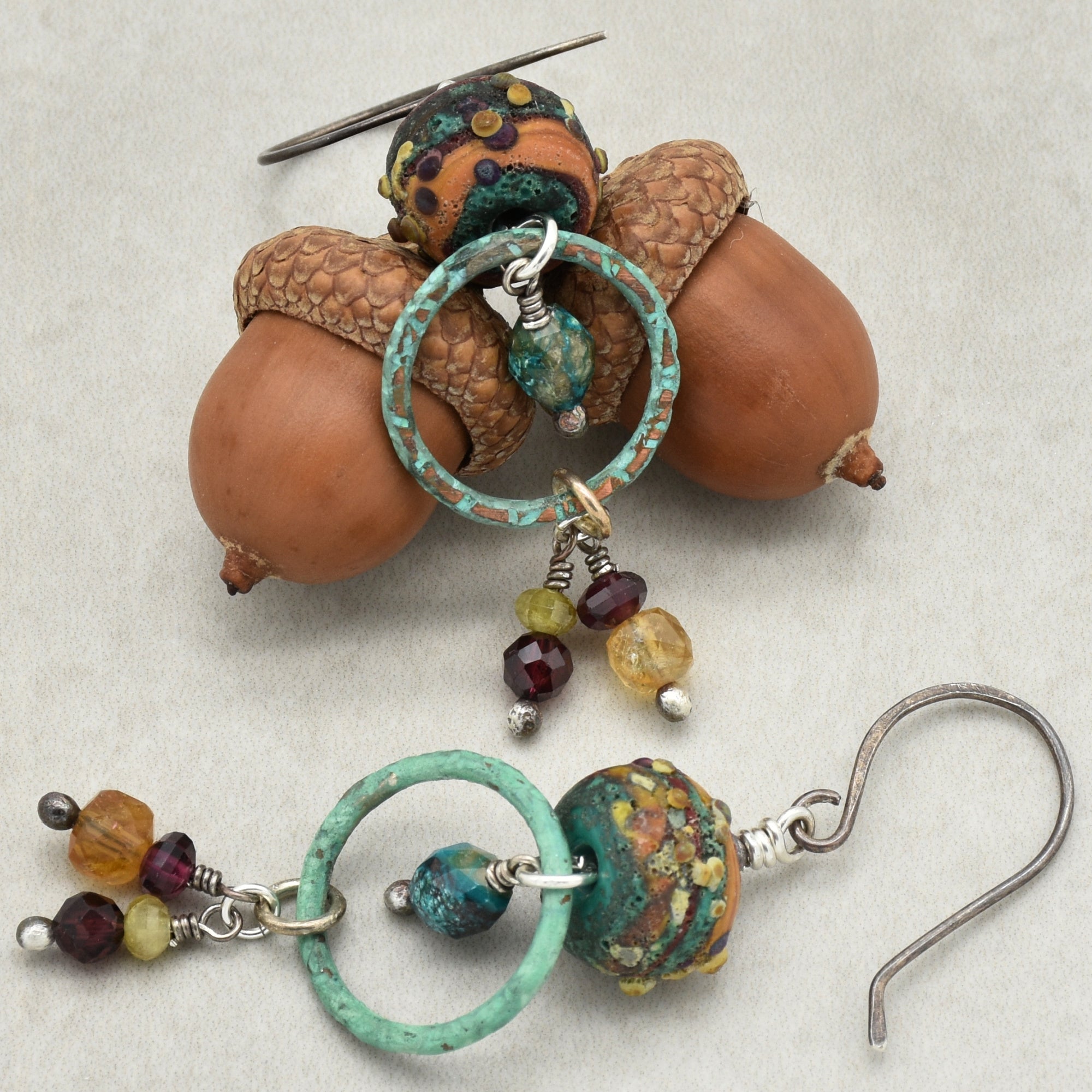 Handmade unique earrings in autumn shades like turquoise, maroon, olive green, golden yellow on a light surface
