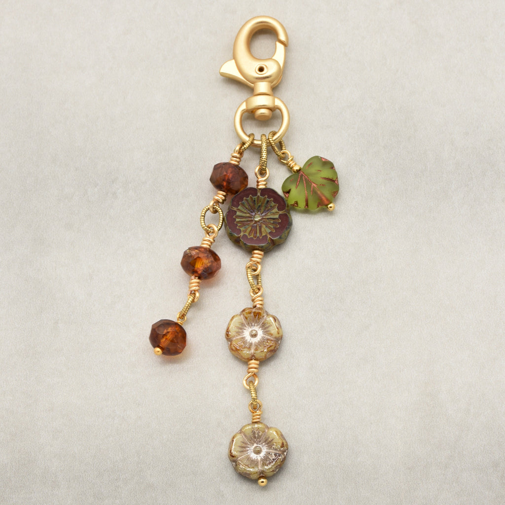 Harvest Bloom Handbag Charm featuring wire-wrapped rust hibiscus flowers and olive green maple leaf charm, handmade by Ruby Acorn