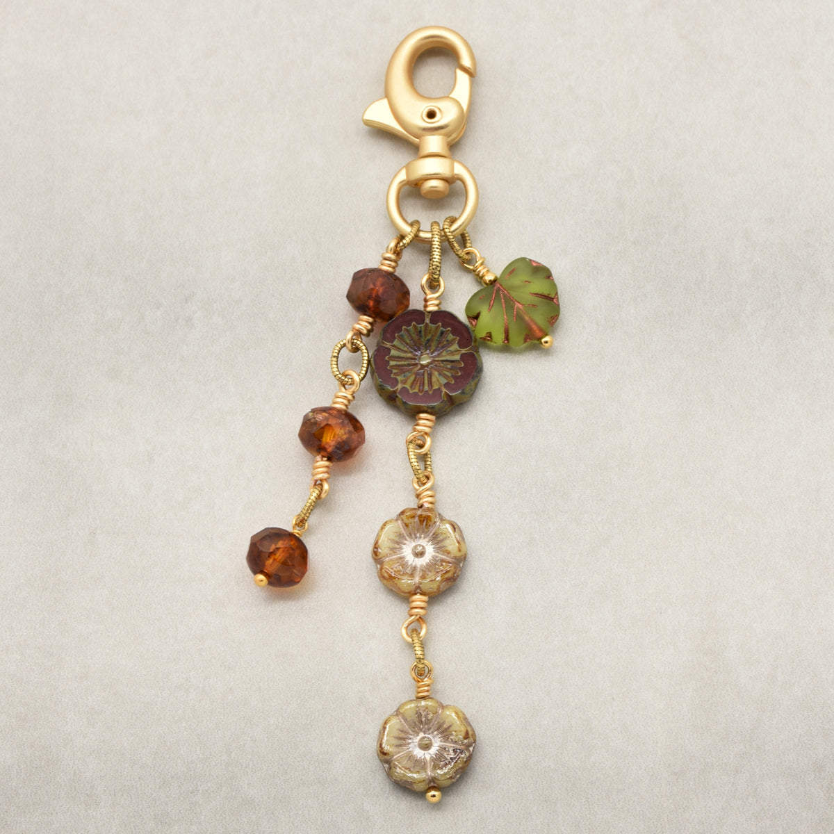 Harvest Bloom Handbag Charm featuring wire-wrapped rust hibiscus flowers and olive green maple leaf charm, handmade by Ruby Acorn