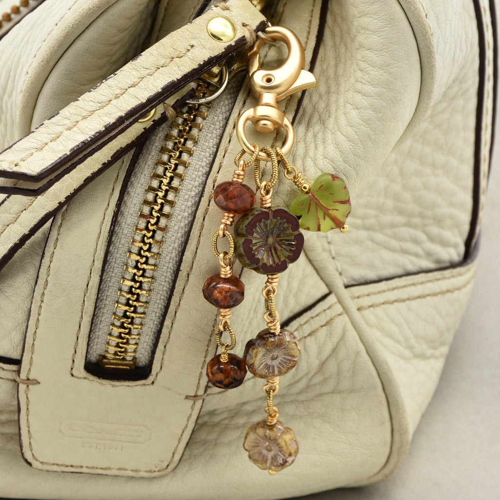Harvest Bloom Handbag Charm featuring wire-wrapped rust hibiscus flowers and olive green maple leaf charm, handmade by Ruby Acorn