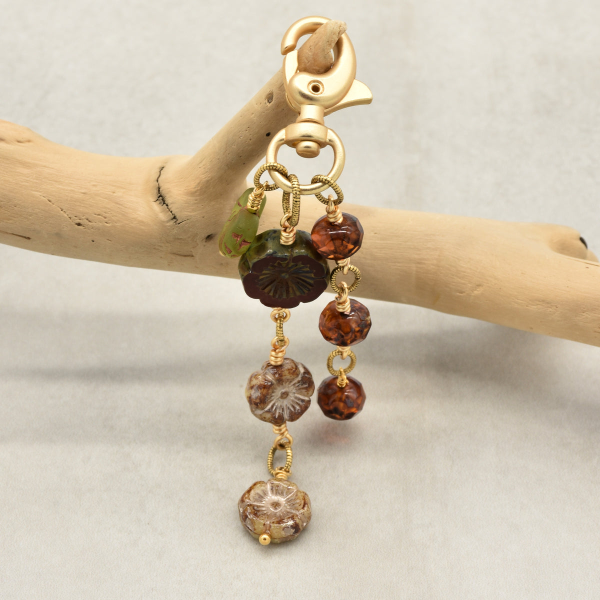 Harvest Bloom Handbag Charm featuring wire-wrapped rust hibiscus flowers and olive green maple leaf charm, handmade by Ruby Acorn