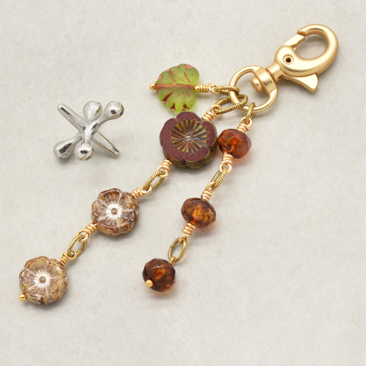 Harvest Bloom Handbag Charm featuring wire-wrapped rust hibiscus flowers and olive green maple leaf charm, handmade by Ruby Acorn