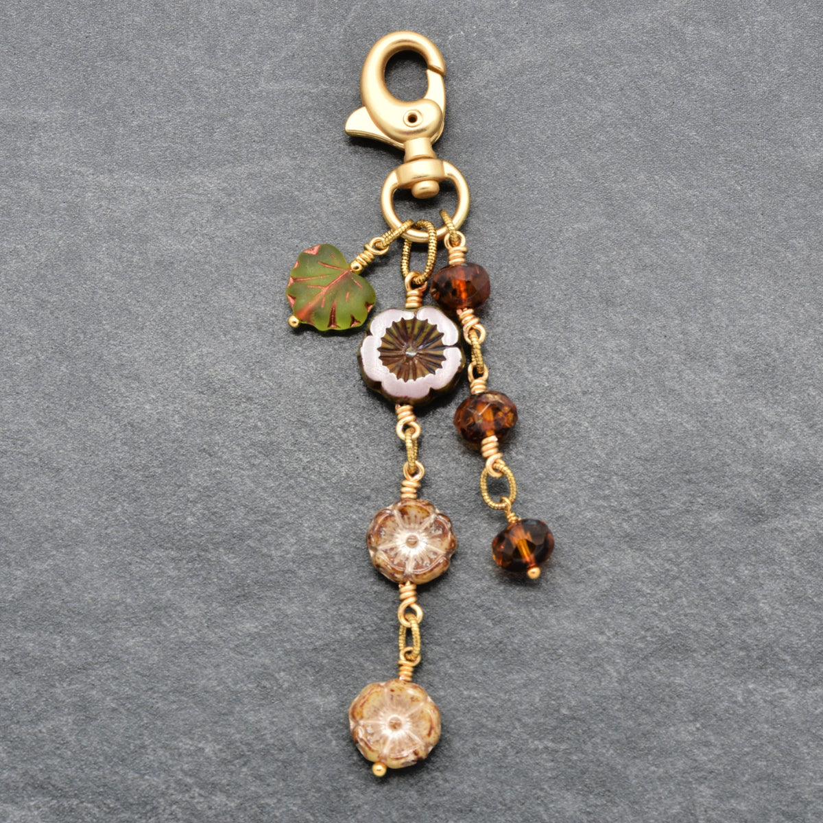 Harvest Bloom Handbag Charm featuring wire-wrapped rust hibiscus flowers and olive green maple leaf charm, handmade by Ruby Acorn
