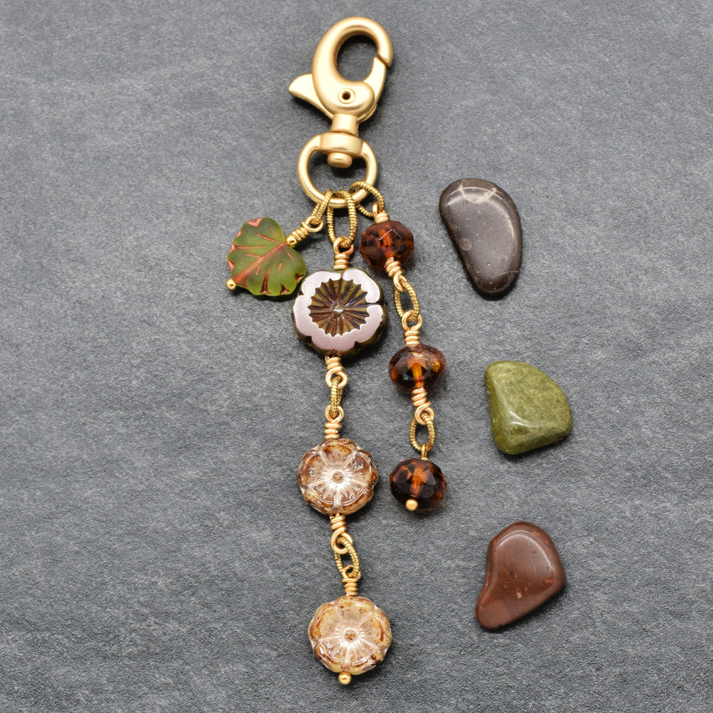 Harvest Bloom Handbag Charm featuring wire-wrapped rust hibiscus flowers and olive green maple leaf charm, handmade by Ruby Acorn