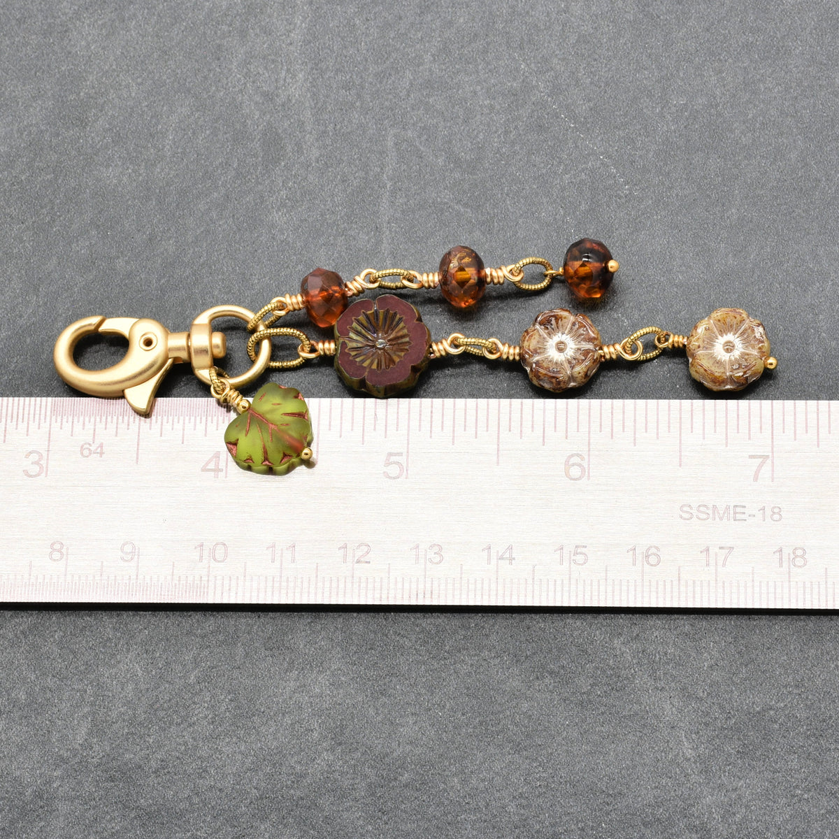 Harvest Bloom Handbag Charm featuring wire-wrapped rust hibiscus flowers and olive green maple leaf charm, handmade by Ruby Acorn