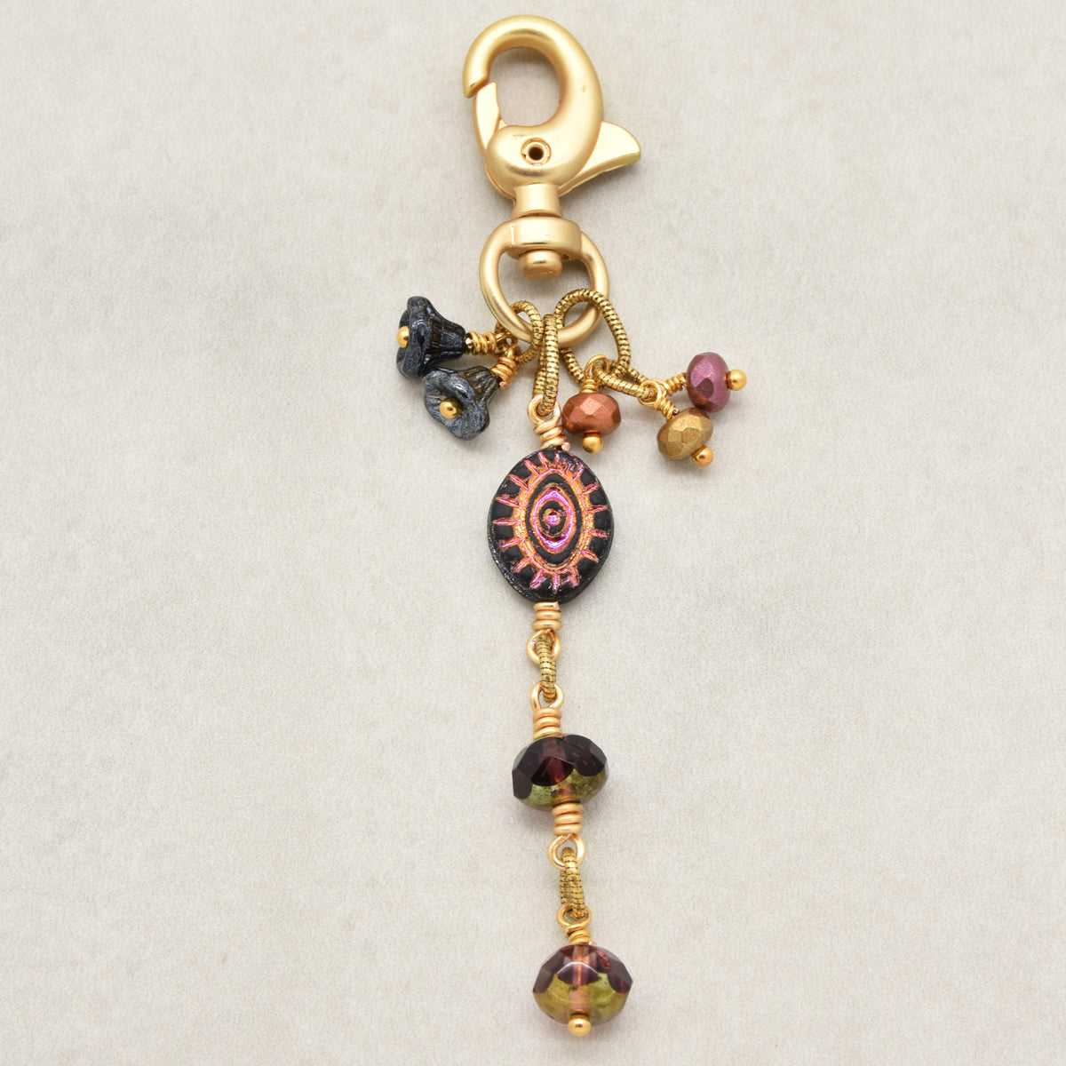 Ember Eye Handbag Charm featuring a graphite gray Czech glass evil eye focal with shimmery copper center, handmade by Ruby Acorn