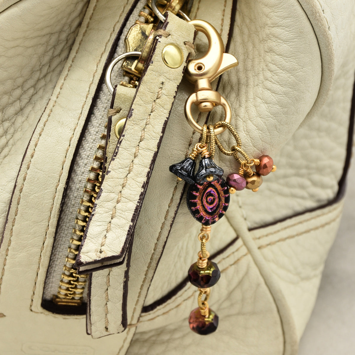 Ember Eye Handbag Charm featuring a graphite gray Czech glass evil eye focal with shimmery copper center, handmade by Ruby Acorn
