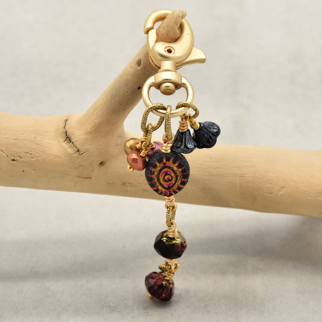 Ember Eye Handbag Charm featuring a graphite gray Czech glass evil eye focal with shimmery copper center, handmade by Ruby Acorn