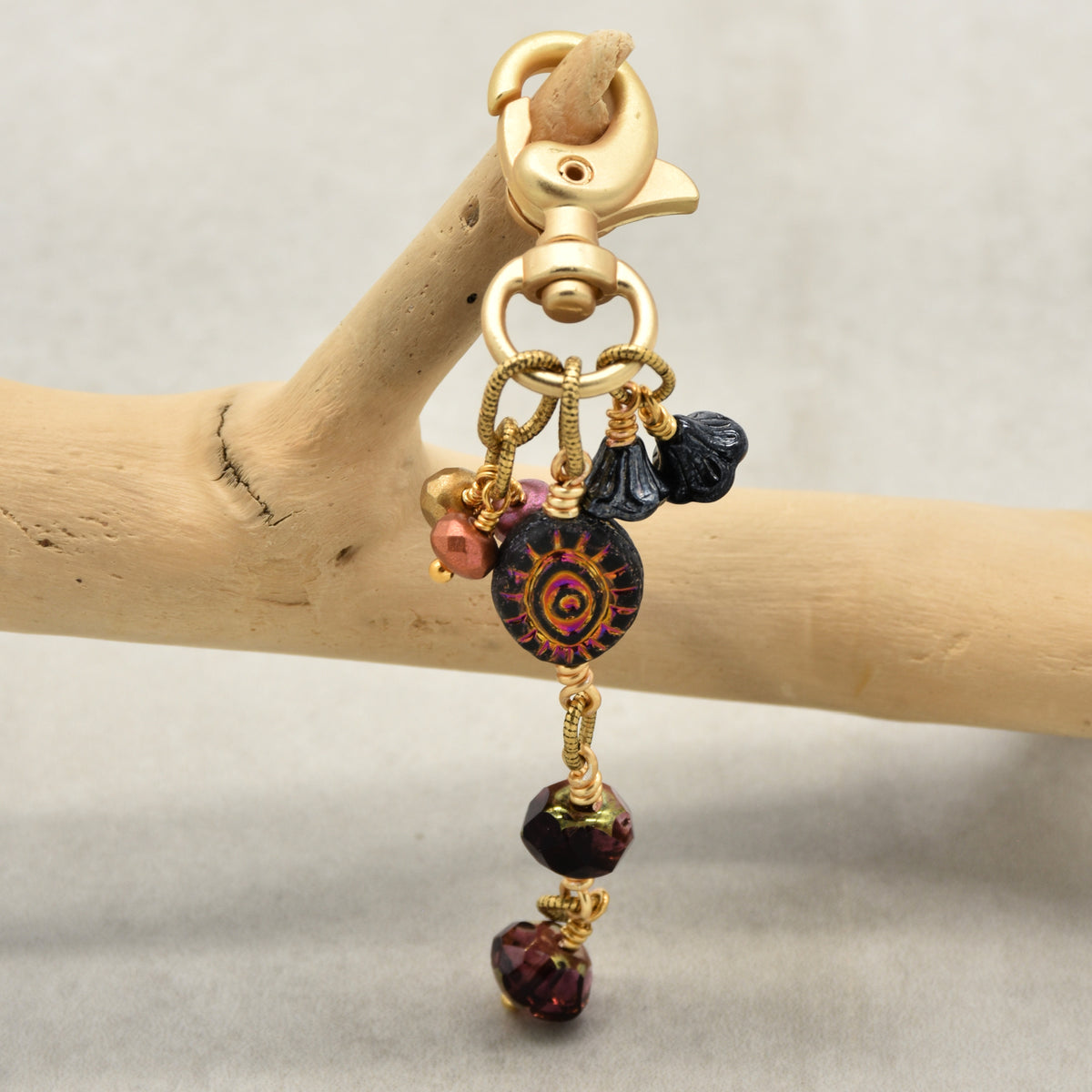 Ember Eye Handbag Charm featuring a graphite gray Czech glass evil eye focal with shimmery copper center, handmade by Ruby Acorn