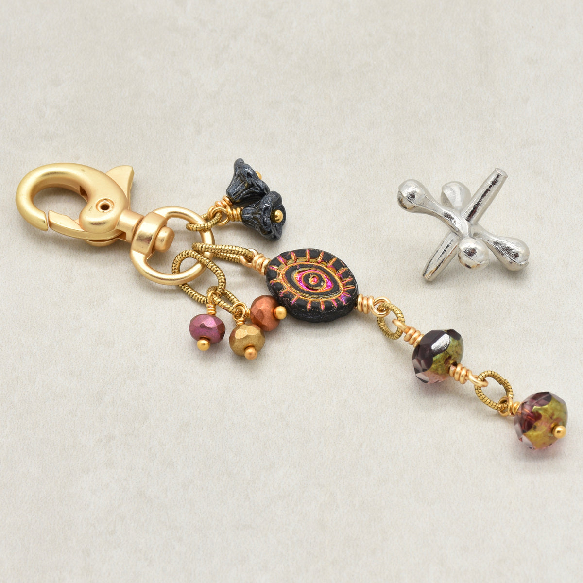 Ember Eye Handbag Charm featuring a graphite gray Czech glass evil eye focal with shimmery copper center, handmade by Ruby Acorn