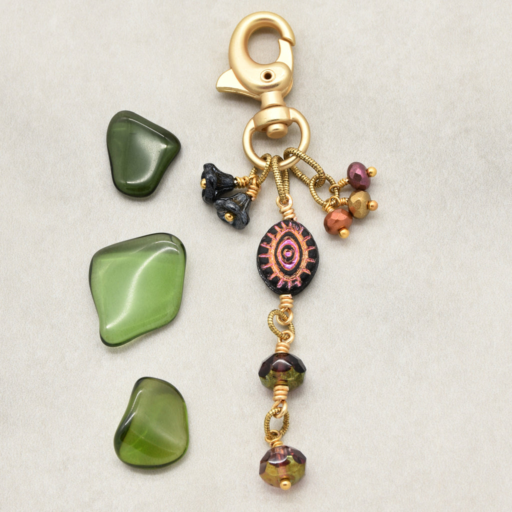 Ember Eye Handbag Charm featuring a graphite gray Czech glass evil eye focal with shimmery copper center, handmade by Ruby Acorn