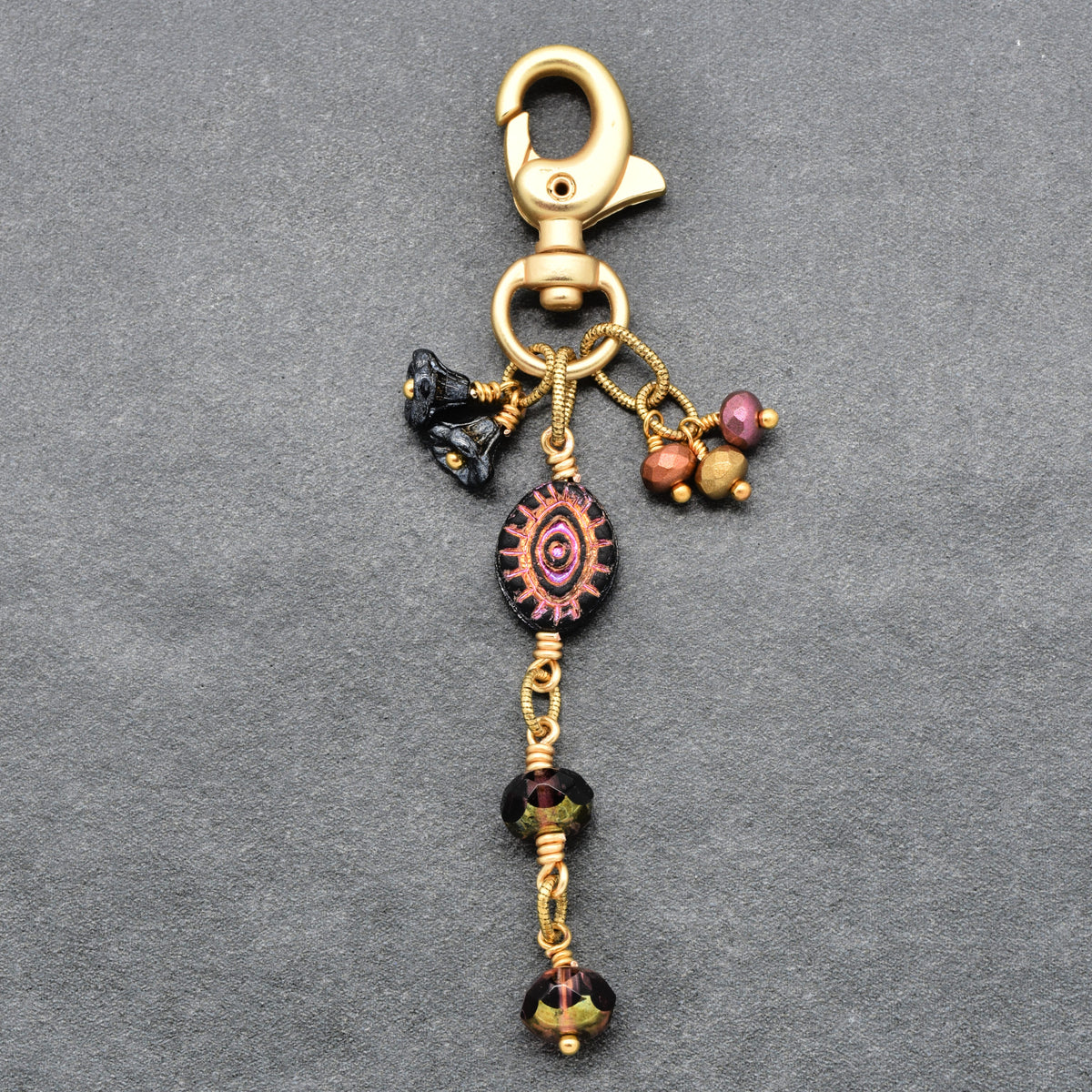 Ember Eye Handbag Charm featuring a graphite gray Czech glass evil eye focal with shimmery copper center, handmade by Ruby Acorn