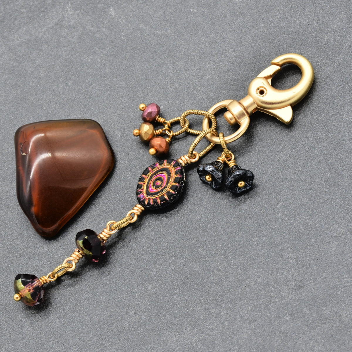 Ember Eye Handbag Charm featuring a graphite gray Czech glass evil eye focal with shimmery copper center, handmade by Ruby Acorn