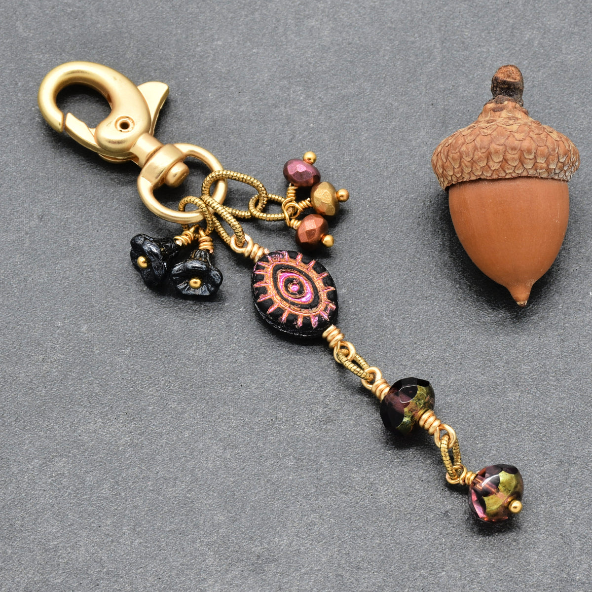 Ember Eye Handbag Charm featuring a graphite gray Czech glass evil eye focal with shimmery copper center, handmade by Ruby Acorn