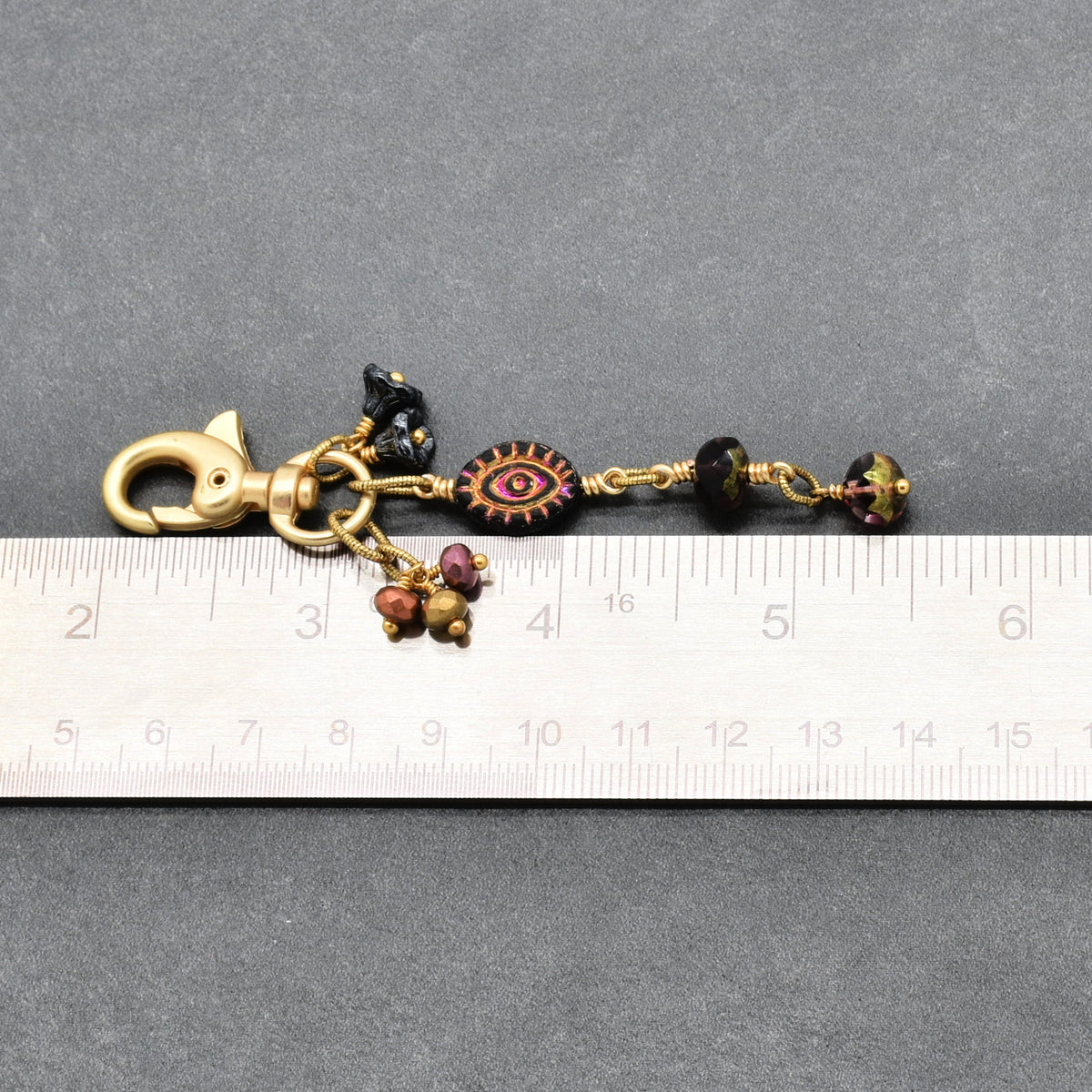 Ember Eye Handbag Charm featuring a graphite gray Czech glass evil eye focal with shimmery copper center, handmade by Ruby Acorn