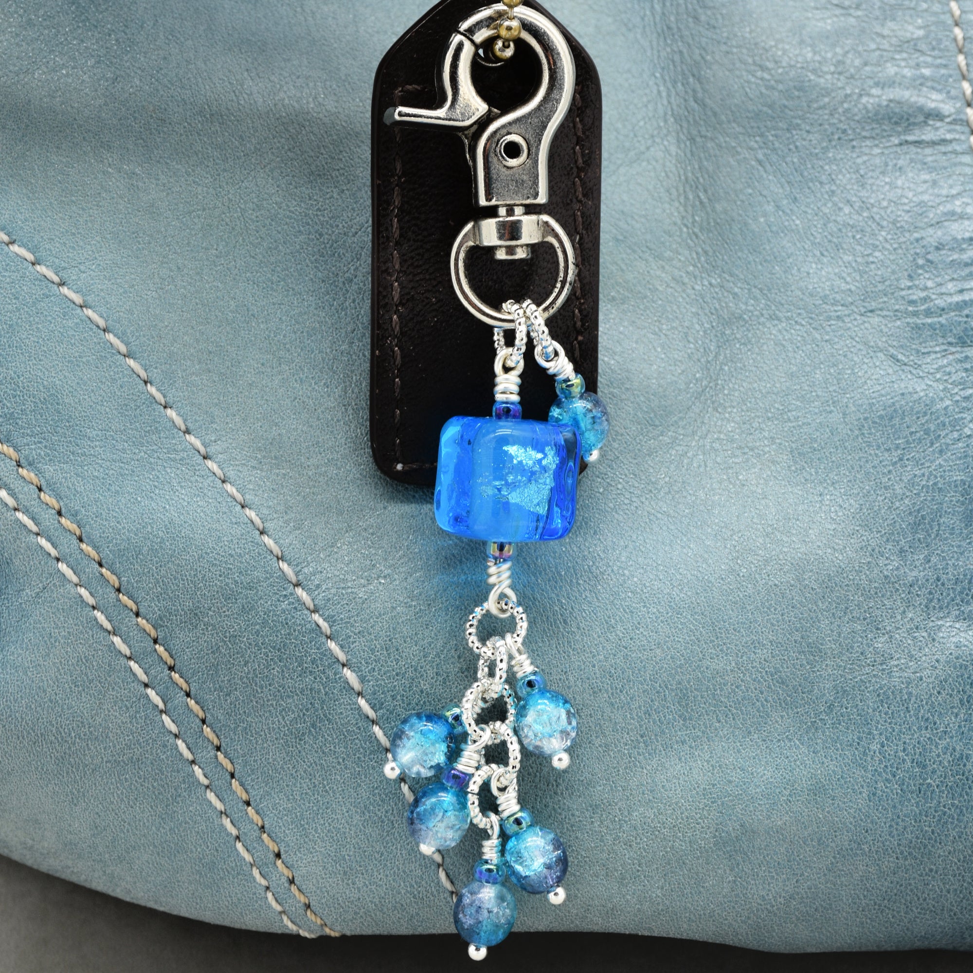 Blue beaded keychain attached to a blue leather background