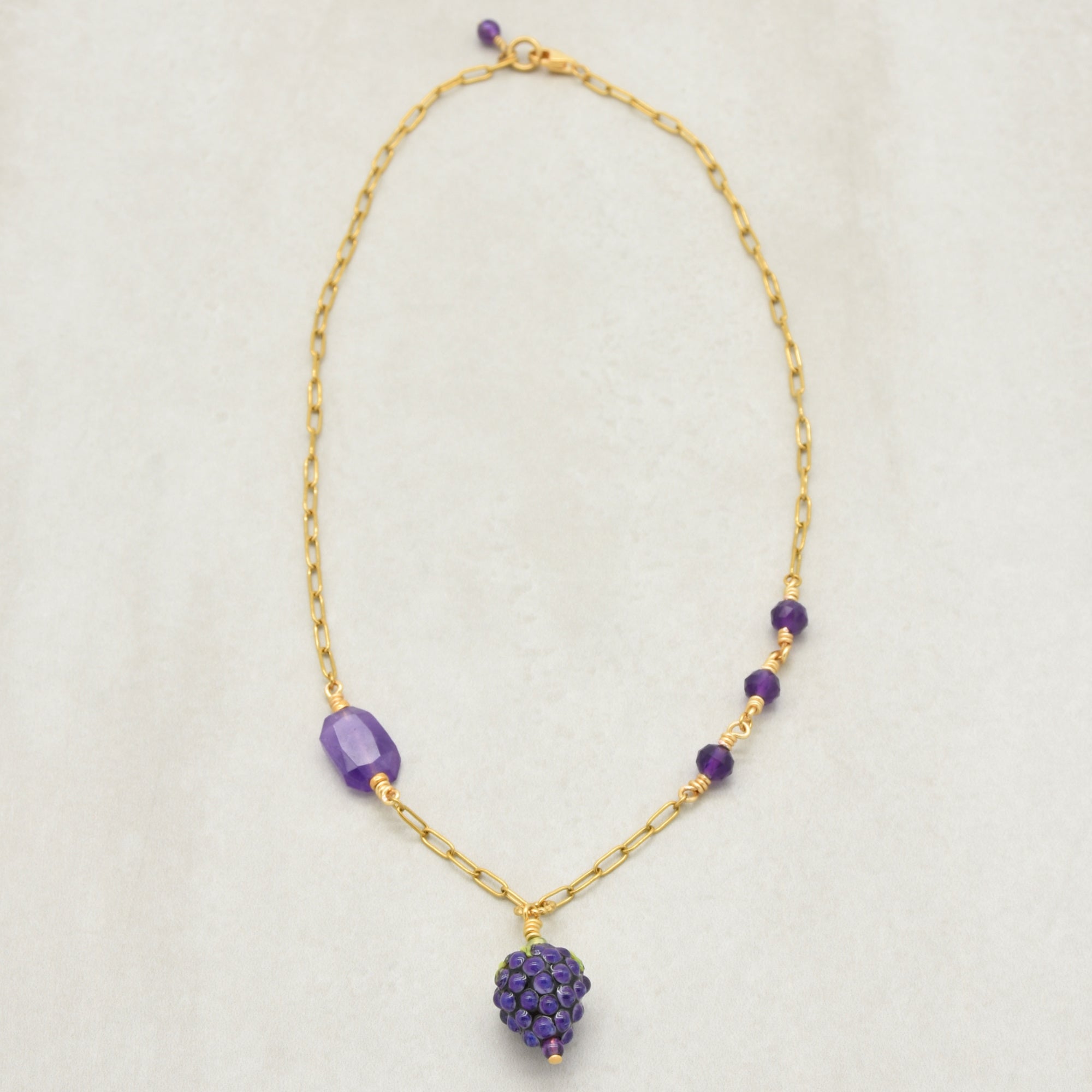 Asymmetrical gold chain necklace with artisan lampwork glass blackberry focal and amethyst on a light background - handmade with love by Ruby Acorn